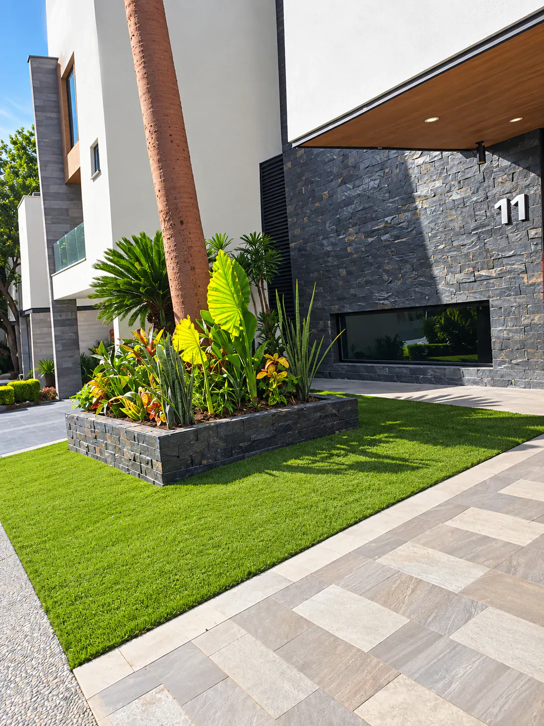 Paisajismo exterior con pasto sintético en un acceso residencial