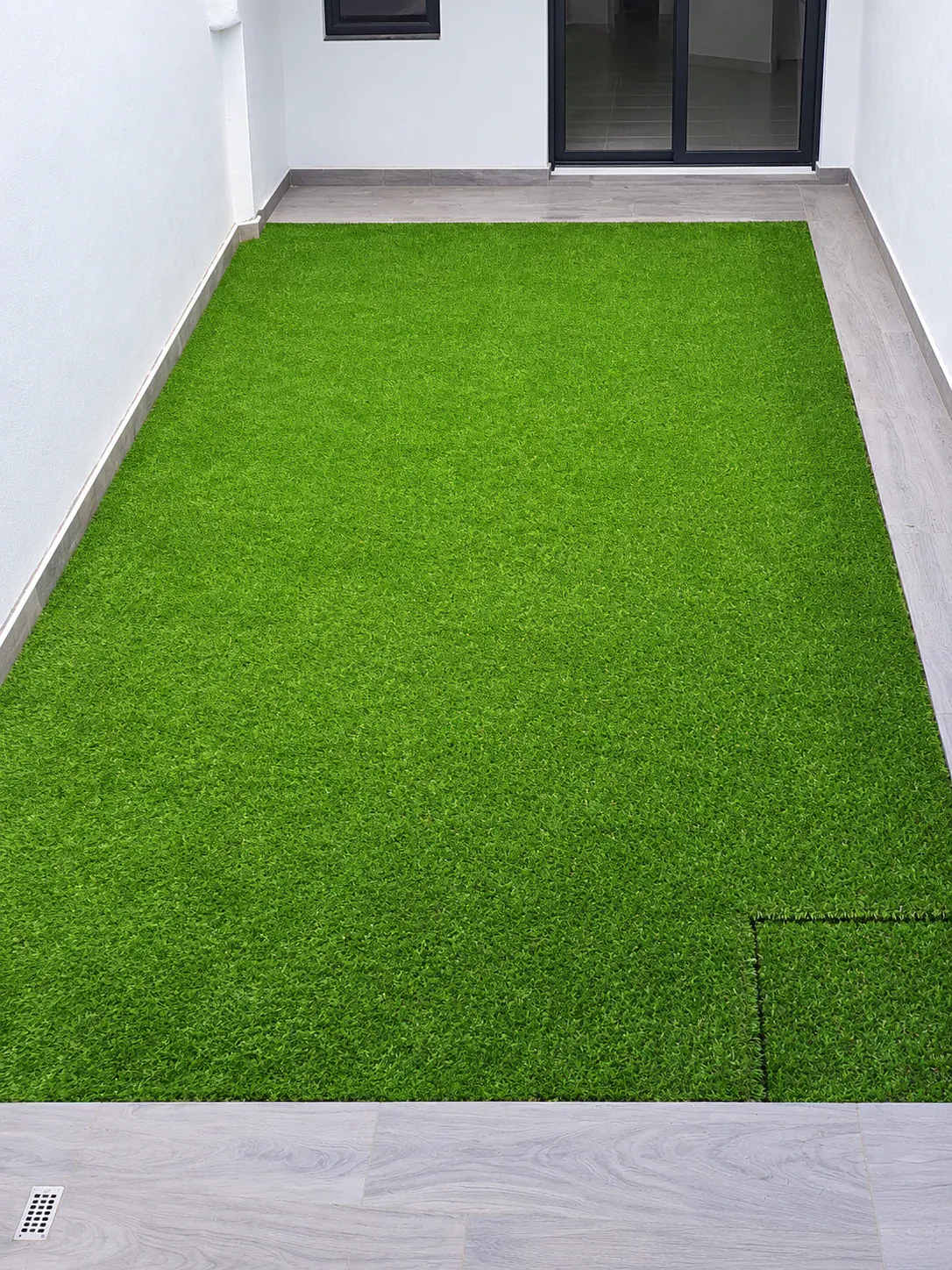 Pasillo lateral residencial cubierto con pasto sintético