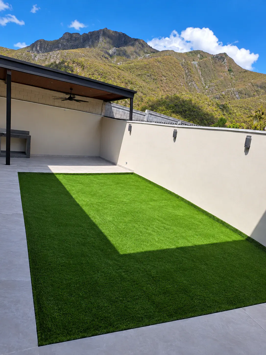 Corredor exterior de vivienda renovado con pasto sintético